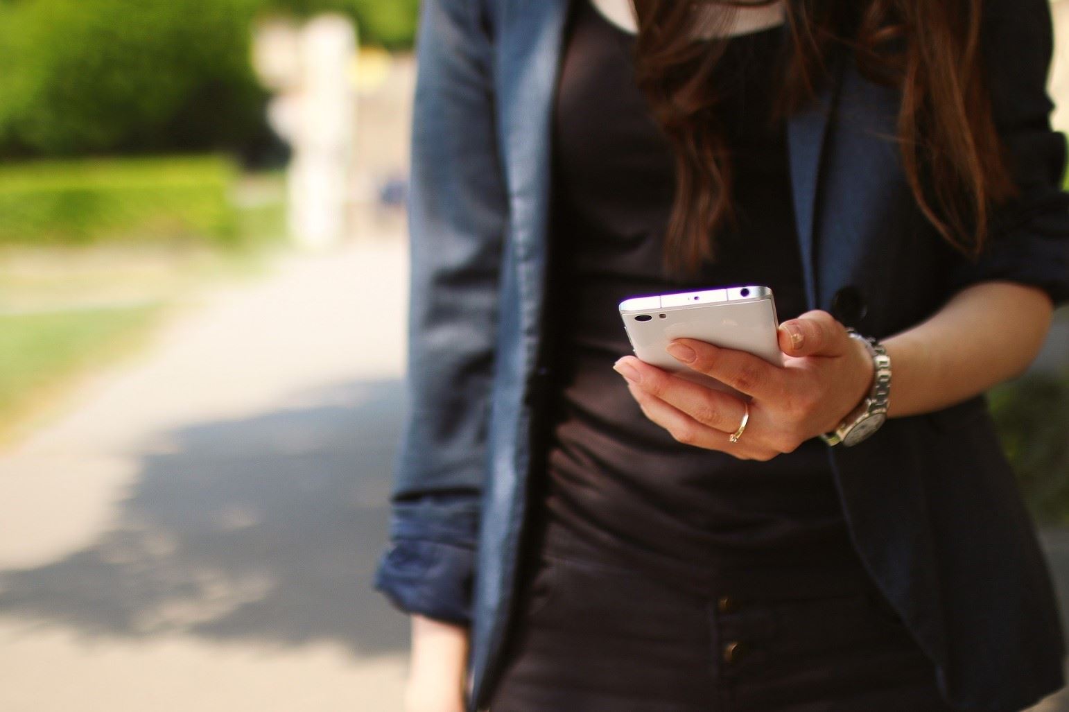 Woman holding and looking at a cell phone while walking