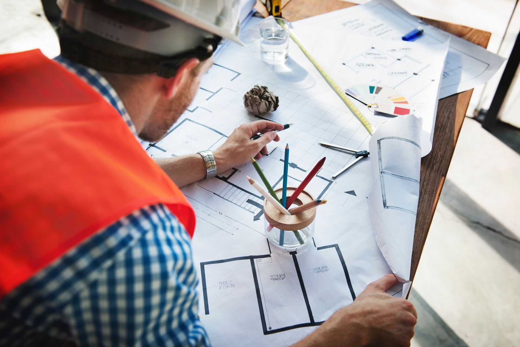 Man wearing a hard hat working on a building schematic