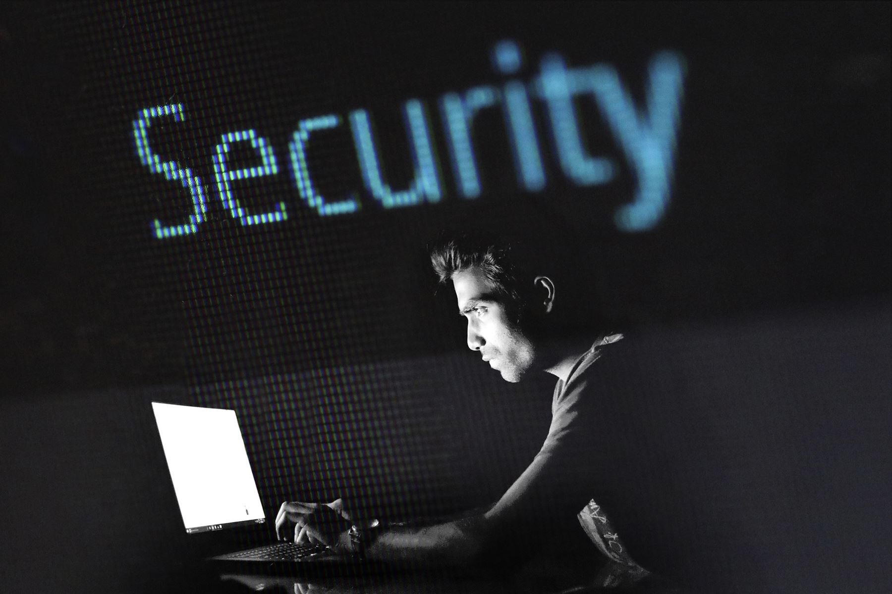 Man typing on a laptop with Security in big blue letters over his head on a screen