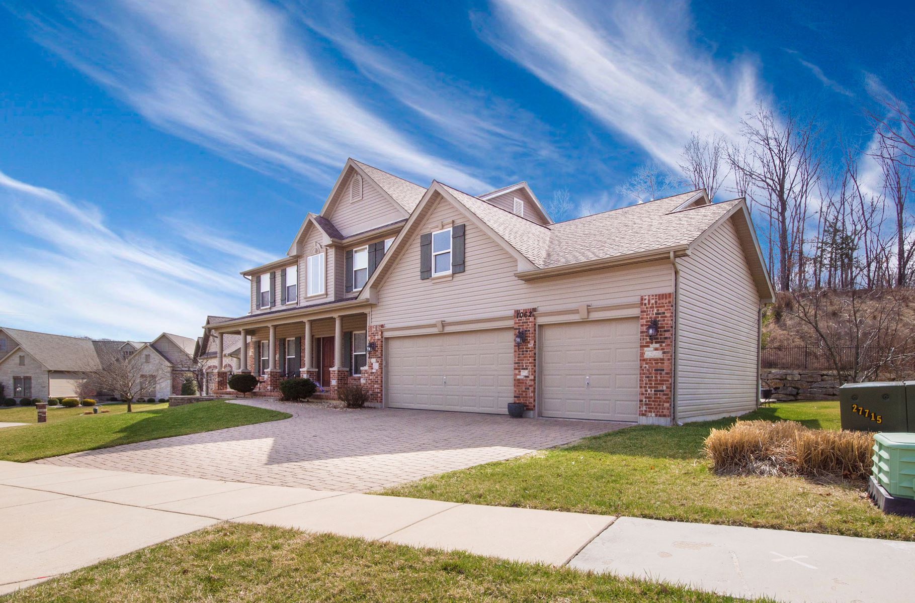 Home that has a 3 car garage, blue sky in the background and green grass in the foreground