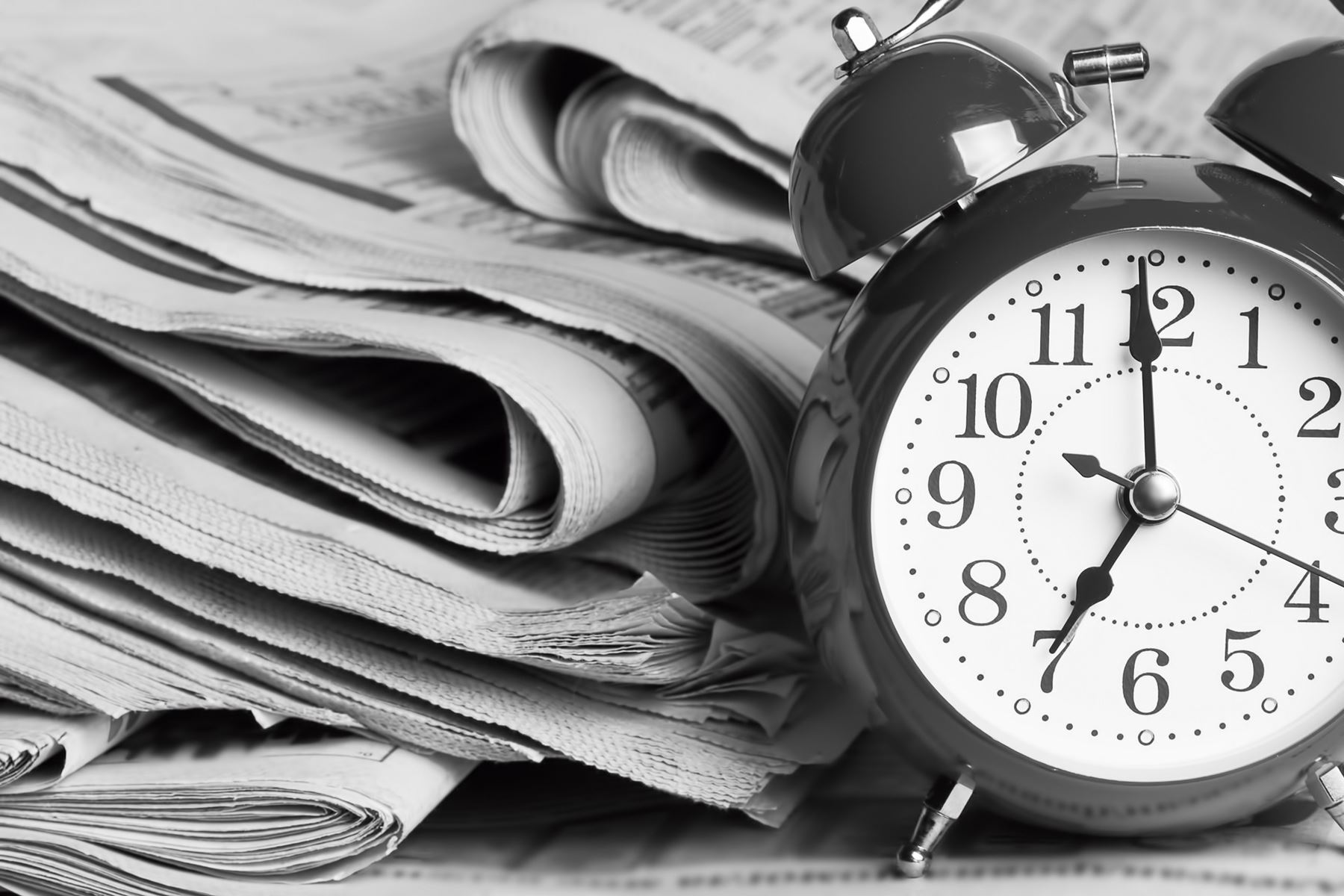 Alarm clock next to a stack of newspapers